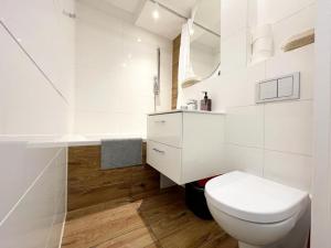 a white bathroom with a toilet and a sink at Apartament Marina Hel in Hel
