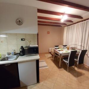eine Küche und ein Wohnzimmer mit einem Tisch und Stühlen in der Unterkunft Melinda nyaralóház in Balatonkenese