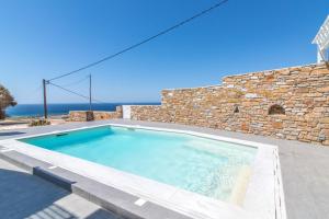 a swimming pool in front of a brick building with the ocean in the background at Epsilon Villa by TinosHost in Tinos Town