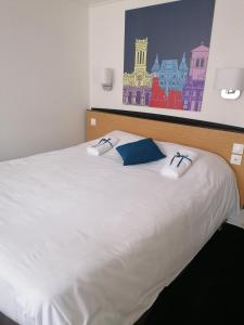 a white bed with a blue pillow on it at Kyriad Blois Nord in Blois