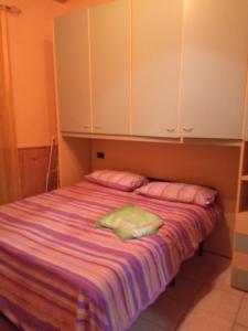 Casa Garage في Roccatederighi: سرير به شراشف وخزانات وردية وأرجوانية