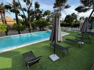 a pool with chairs and umbrellas next to a pool at Los Almendros - Free Parking in Córdoba