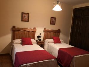 1 dormitorio con 2 camas con sábanas rojas y blancas en EL LABRIEGO, Casa rural, en Fuente el Fresno