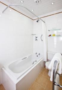 baño blanco con bañera y aseo en La Villette Hotel en St Martin Guernsey