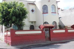 una cerca roja frente a una casa blanca en Habitaciones 1 acceso independiente y autonomo Puebla, en Puebla