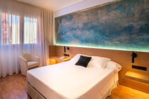 Hotel Rosa & Spa Begur في بيغور: غرفة نوم بسرير ولوحة كبيرة على الحائط