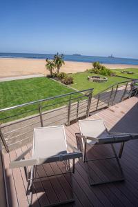 Langstrand的住宿－Deja Blue Beachfront Villa, Newly renovated，甲板上配有两把椅子和一张桌子,俯瞰着海滩