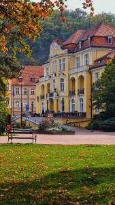 a large yellow building with a bench in a park at TEPLA in Teplice