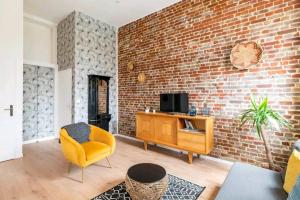 a living room with a brick wall and a yellow chair at 4 Spacieux, chaleureux, hyper centre 300m de la mer in Dieppe