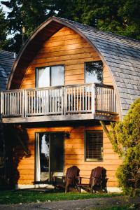 a log cabin with a balcony and two chairs at Ocean Village Resort in Tofino