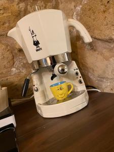 una macchinetta del caffè con una tazza gialla sopra di Dimora Pietra Antica a Bari