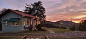 uma pequena casa com um pôr-do-sol ao fundo em Pouso Mantiqueira em Cunha