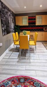 a dining room with a table and yellow chairs at 4 bedroom House Coventry Sleep 9 + 3Parking spaces in Coundon