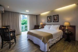 a bedroom with a bed and a desk and a window at Grande Hotel Canela in Canela