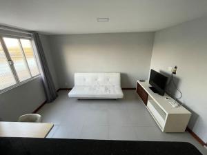 uma sala de estar com um sofá branco e uma televisão em Apartamento Lagoa de Saquarema em Saquarema