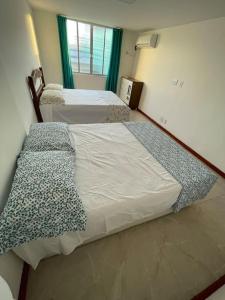 two twin beds in a room with a window at Apartamento Lagoa de Saquarema in Saquarema