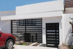 une maison blanche avec une porte noire et une voiture rouge dans l'établissement Alojamiento Altos del Pacífico, à Iquique