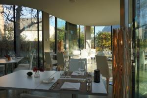 ein Restaurant mit weißen Tischen, Stühlen und Fenstern in der Unterkunft Hôtel de la Poste Sierre in Sierre