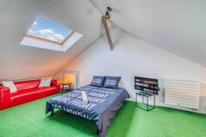 a attic bedroom with a bed and a red couch at Villa Saint-Mard - King Size bed - 10min Aéroport CDG 25min Paris by train in Saint-Mard