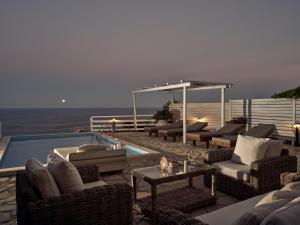 un patio con sofás y sillas y una piscina en Orfos Villas, en Agios Nikolaos