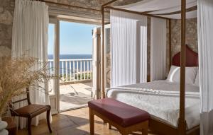 a bedroom with a canopy bed and a balcony with the ocean at Orfos Villas in Agios Nikolaos