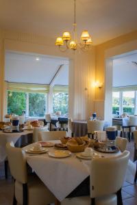 uma sala de jantar com mesa, cadeiras e janelas em Hotel Bos en Duinzicht em Nes