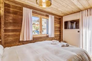 a bedroom with a bed and a window at Le Hameau des Cimes - Welkeys in Megève