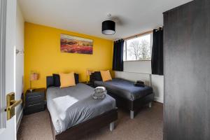 1 dormitorio con 2 camas y pared amarilla en 3 Bedroom Home l Free Parking l Long and Short Term Stays, en Wigan