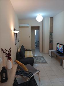 een woonkamer met een bank en een tv bij Happy holiday apartment in Artemida