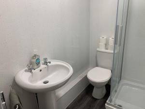 een witte badkamer met een toilet en een wastafel bij 42 NELSON ST in Largs