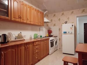 a kitchen with wooden cabinets and a white refrigerator at Квартиры на Подоле in Poltava