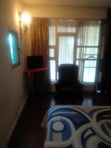 een slaapkamer met een bed, een stoel en een raam bij Recamara en Polanco (solo hombres) in Mexico-Stad