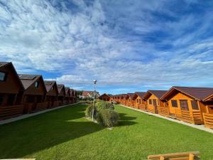 eine Reihe von Holzhäusern mit grünem Rasen in der Unterkunft Domki Korsarz Gaski in Gąski