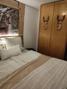 sypialnia z łóżkiem z dwoma głowami jeleni na ścianie w obiekcie Entspannung pur mit DaheimGefühl w mieście Baiersbronn