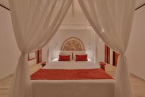 a bedroom with a white bed with red pillows at Pousada Xalés de Maracaípe in Porto De Galinhas