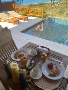 una mesa con platos de comida en una mesa cerca de una piscina en Canta La Rana, en Bejuco