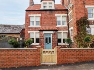 una casa de ladrillo con una puerta azul y una valla de ladrillo en Arden House, en Whitby