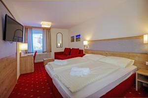 Habitación de hotel con cama grande y sofá rojo. en Kirchenwirt Schladming, en Schladming