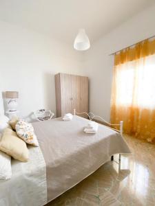 uma cama branca num quarto com uma janela em Gioffredi Apartment em Manduria