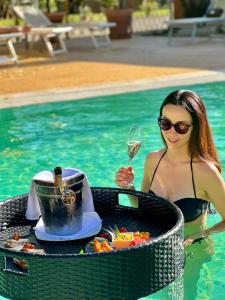a woman in a swimming pool with a table of food and a glass of wine at Cortona Resort & Spa - Villa Aurea in Cortona