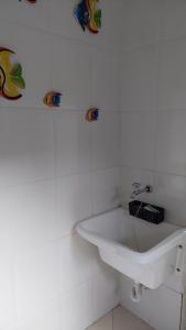 ein weißes Waschbecken in einem weiß gefliesten Bad in der Unterkunft Casa aconchegante com ar condicionado para família em condomínio in Caraguatatuba + 22 Fotos