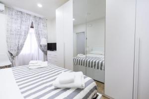 a white bedroom with two beds and a mirror at Contrasto Apartments in Viterbo