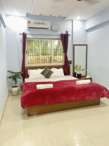 a bedroom with a large bed with a red blanket at Seashore Holiday Home in Revadanda