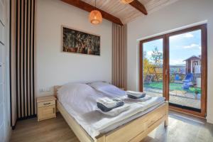 een slaapkamer met een bed en een groot raam bij Dom na Wzgórzu SŁOŃCE na wyłączność JACUZZI ELEKTRYCZNE SAUNA ROWERY in Zawóz