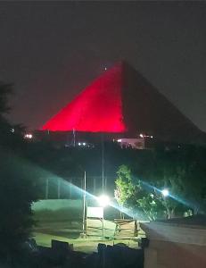 a pyramid is lit up red at night at Ramses Guest House in Cairo