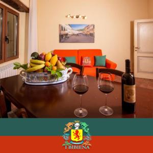 a table with a bowl of fruit and two glasses of wine at IBibiena - SUITE DI DIEGO in Bibbiena