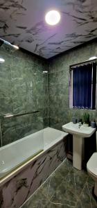 a bathroom with a bath tub and a sink at 4 bedroom House Coventry Sleep 9 + 3Parking spaces in Coundon