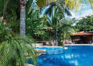 a swimming pool with palm trees in a resort at Upscale 2bdr with Jacuzzi - Beach - Fast wifi - Gym in Tamarindo