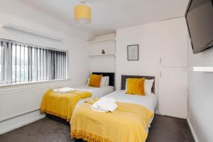 Cressingham House Manchester في مانشستر: سريرين في غرفة بيضاء مع ملاءات صفراء