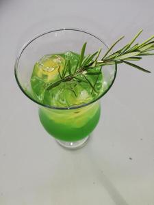 uma taça de vidro com uma bebida verde com um ramo de alecrim em Cosy Garden em Maseru